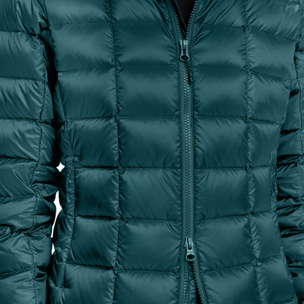 Close-up of a dark teal-green quilted puffer jacket with a front zipper, showing the padded grid pattern and fabric texture.