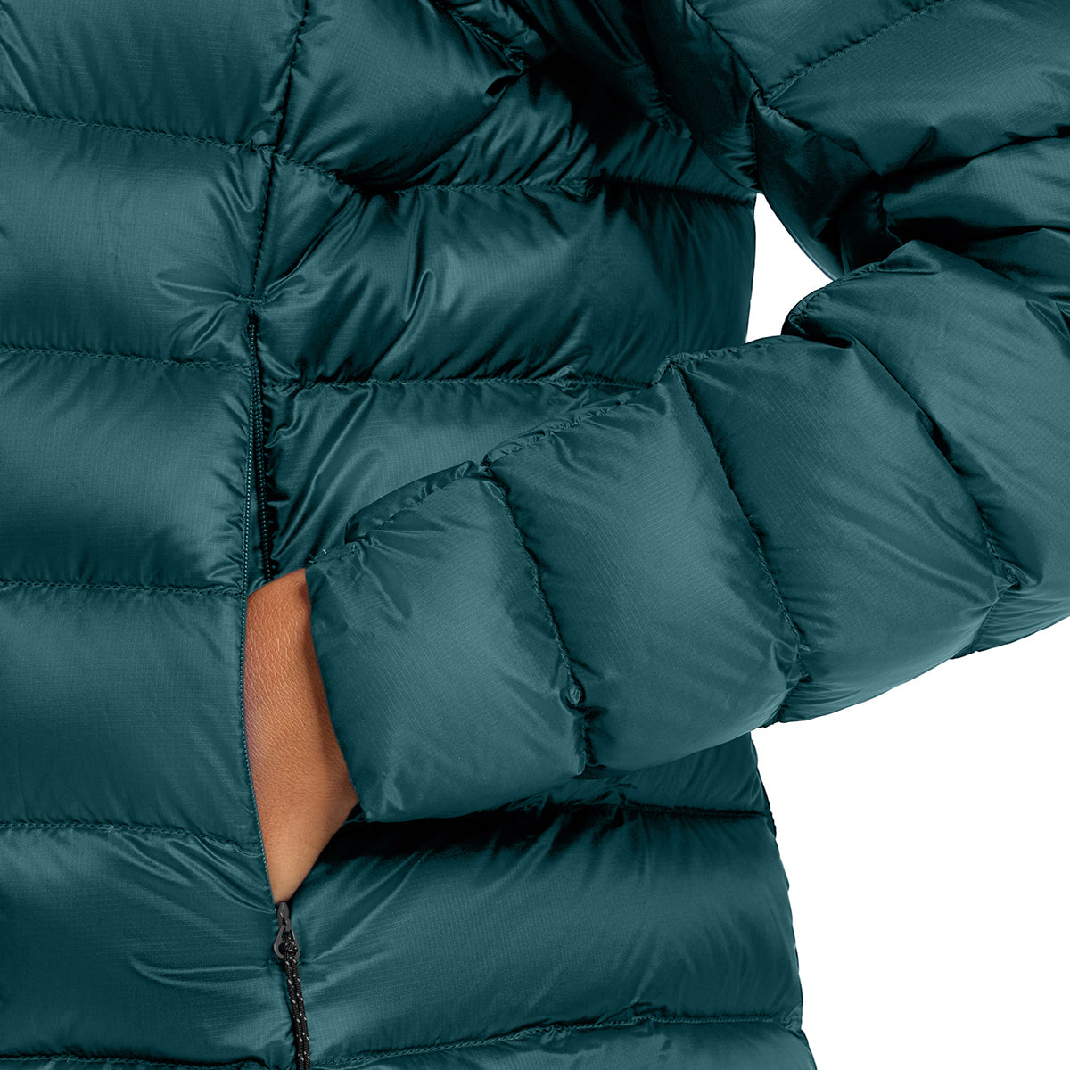 Close-up of a dark teal-green puffer jacket with horizontal quilting, showing a hand in the side pocket against a white background.