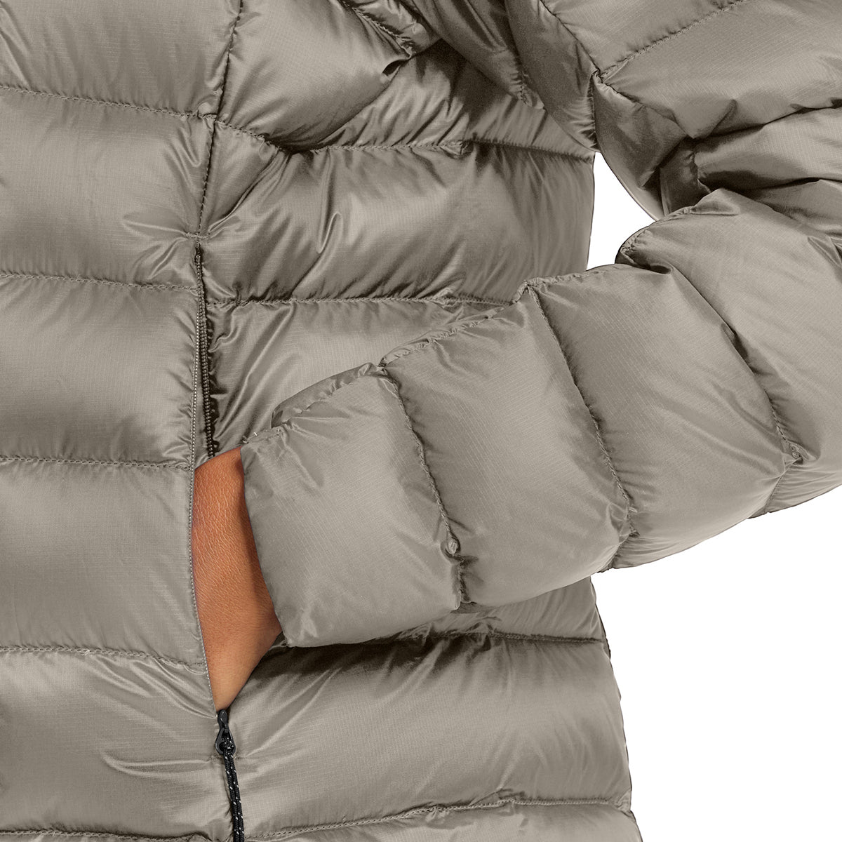 Close-up of a puffer jacket in a warm gray or taupe color, showing the quilted texture and a hand tucked into the side pocket.