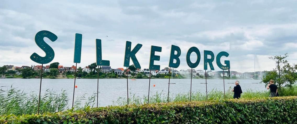 Large Silkeborg sign in front of a lake at the Danish Outdoor Festival.