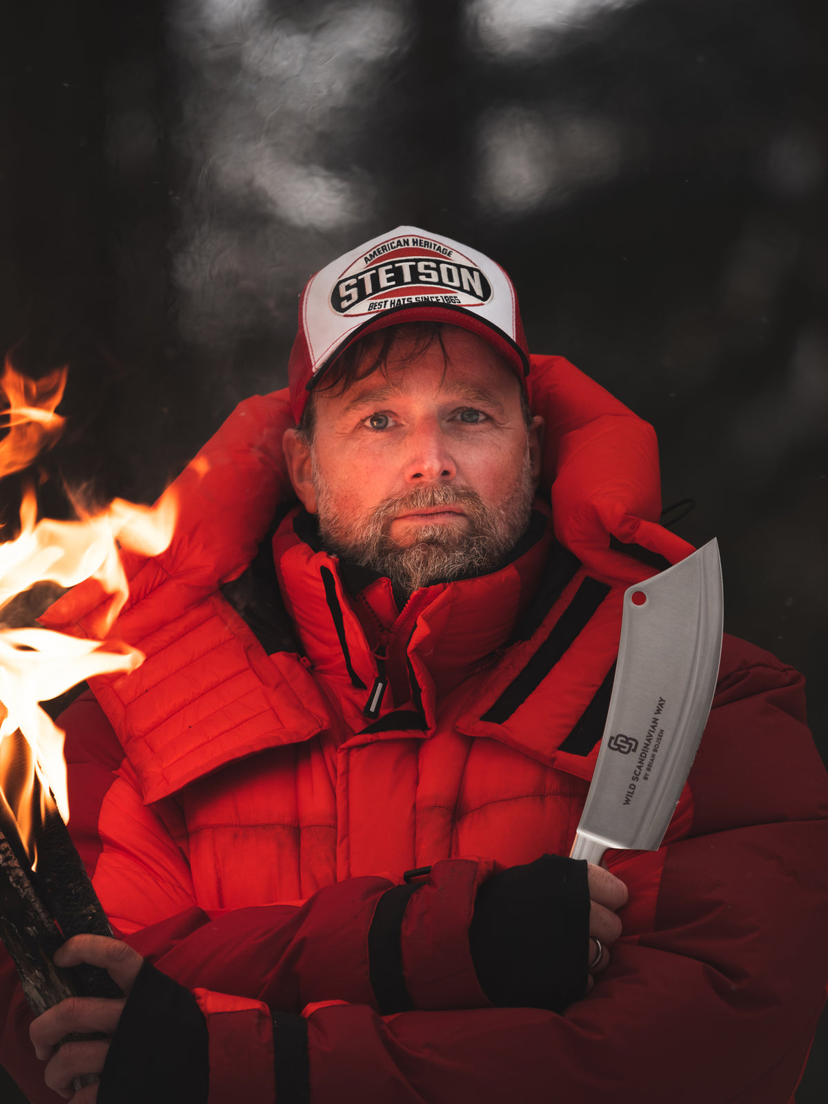 Nordisk Hero Brian Bojsen wearing a red jacket, holding a knife and a torch.