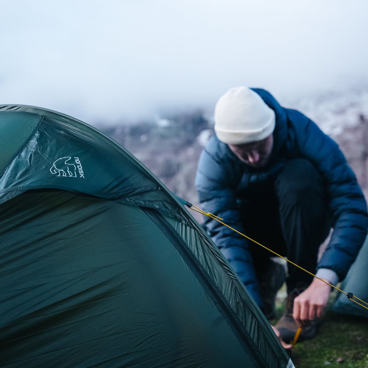 Man setting up a green Nordisk tent while wild camping in Peru.