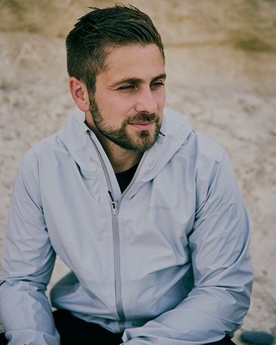 Portrait of a man wearing a Nordisk outdoor hooded jacket for hiking and camping adventures.