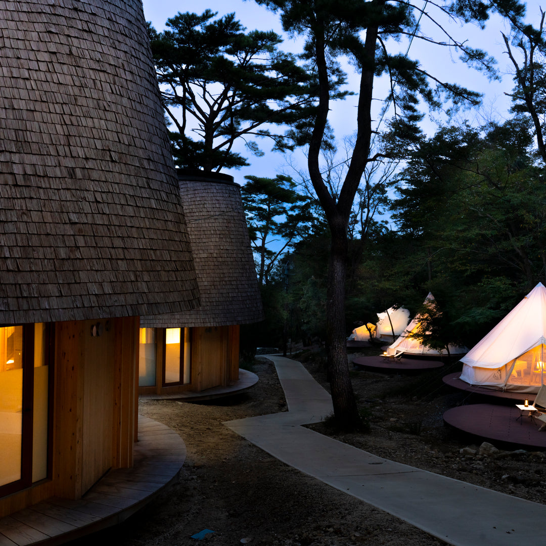 Sustainable wooden cabins and glamping tents at Nordisk Hygge Circles Ugakei in Japan at night.
