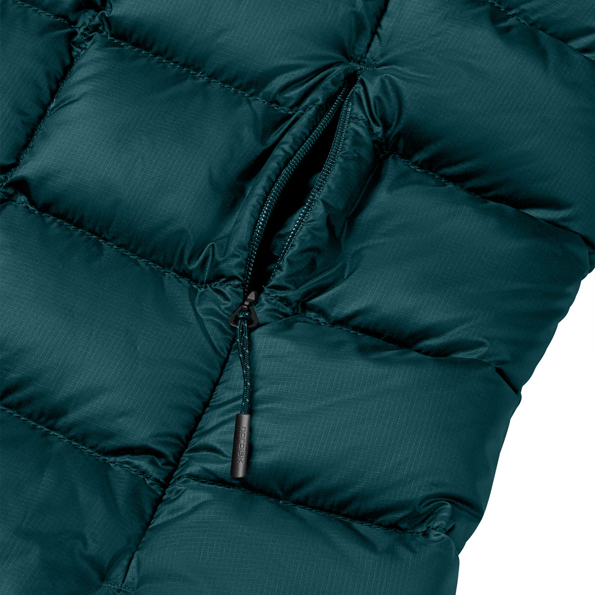 Close-up of a dark teal-green puffer jacket showing quilted stitching, a zippered pocket, and a small dark zipper pull tab on a white background.