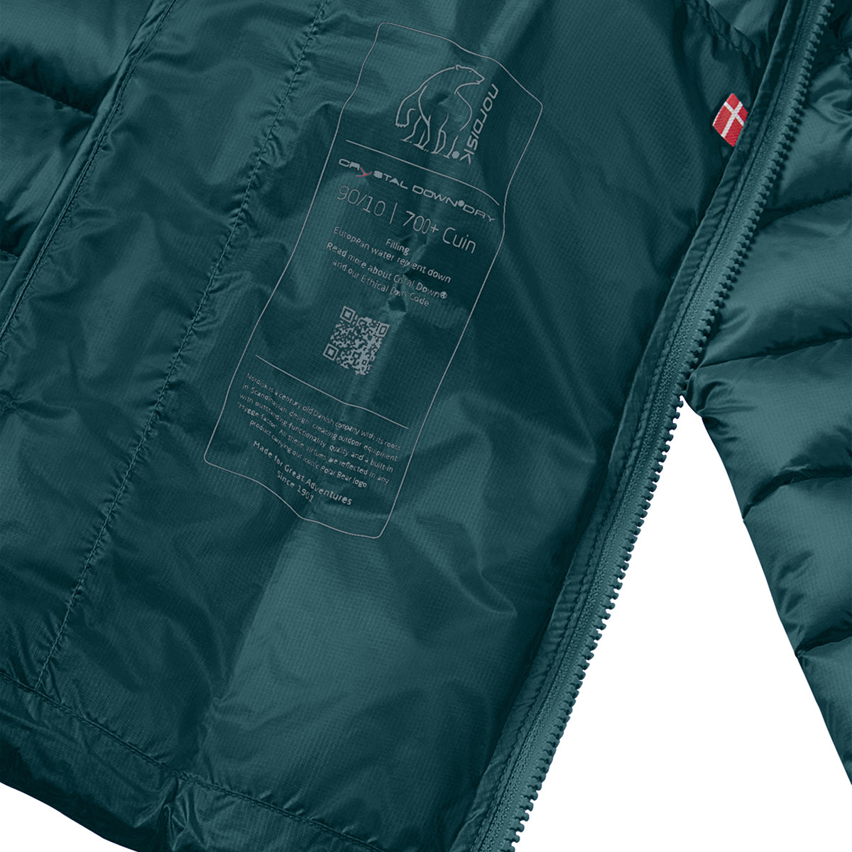 Close-up of a dark teal puffer jacket interior showing a transparent printed hangtag with product details and a small red square logo near the zipper.