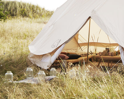 Large Nordisk glamping tent with a cozy interior setup in a grassy outdoor landscape.