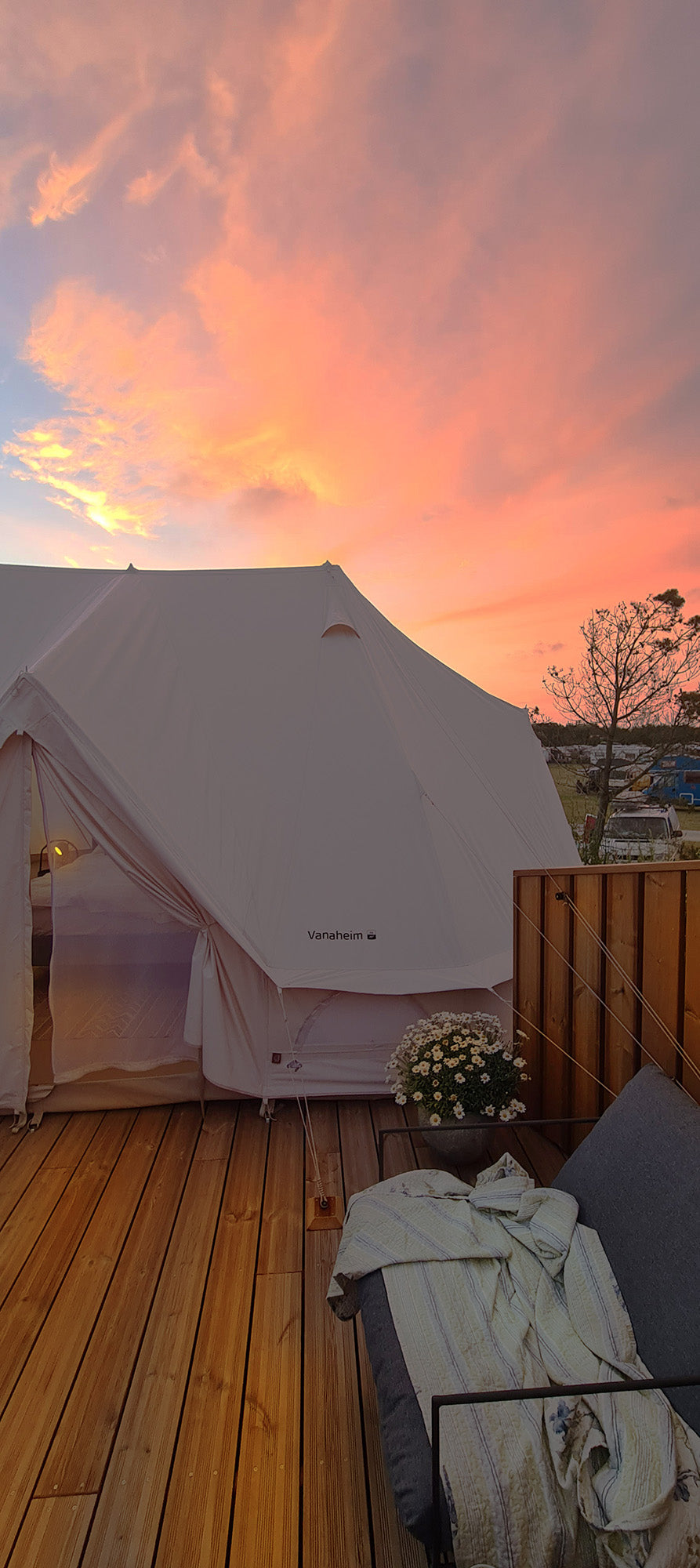 Luxurious Nordisk Vanaheim glamping tent on a wooden deck during a colorful sunset in Denmark.