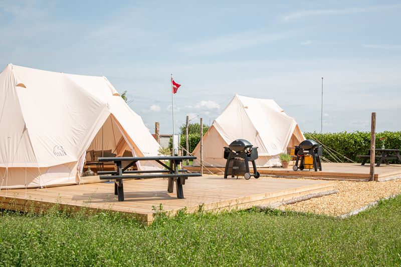 Luxurious Nordisk cotton glamping tents with wooden decks and picnic tables at Rødgård Camping.