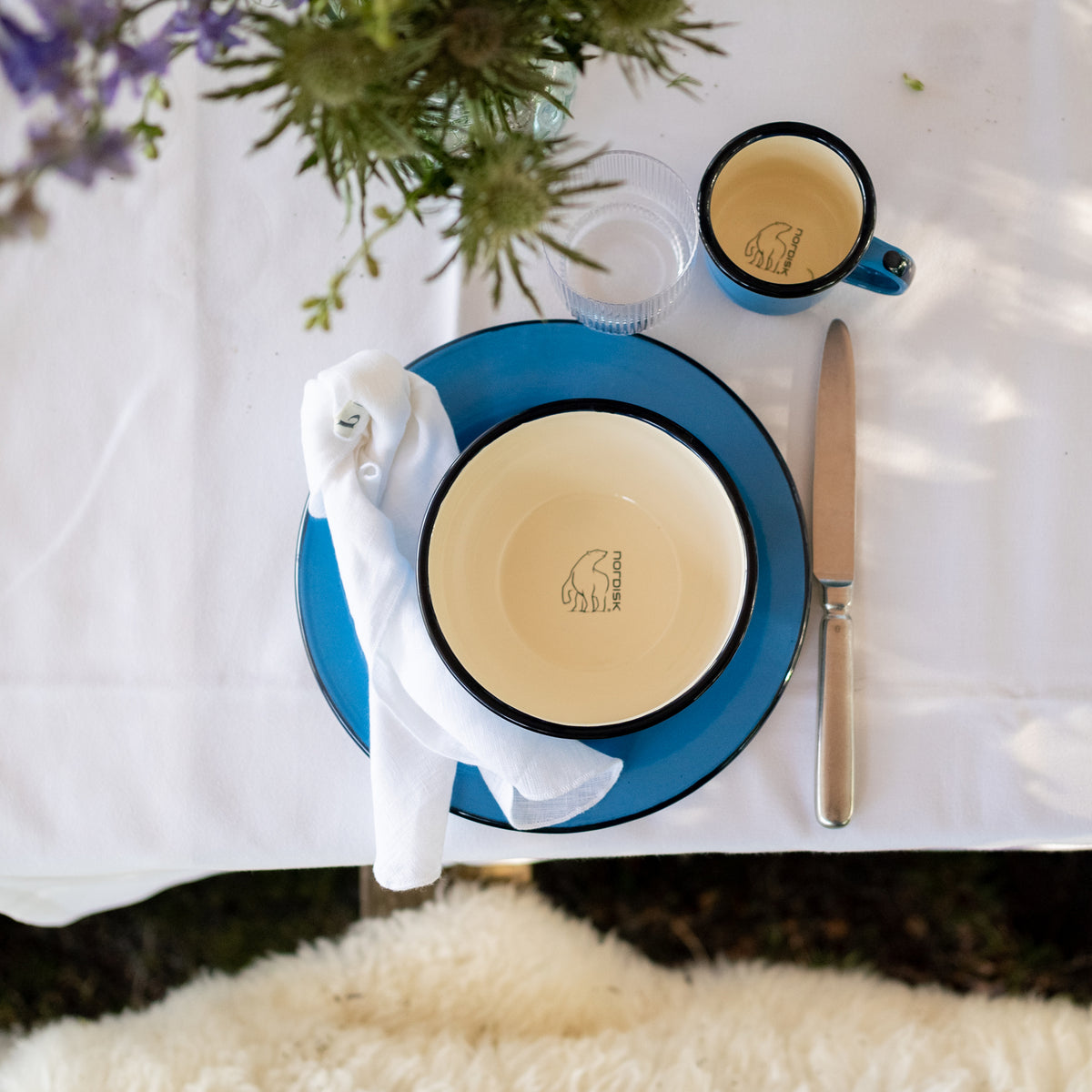 Nordisk Madam Blå enamel bowl, plate, and cup set on a white table setting.