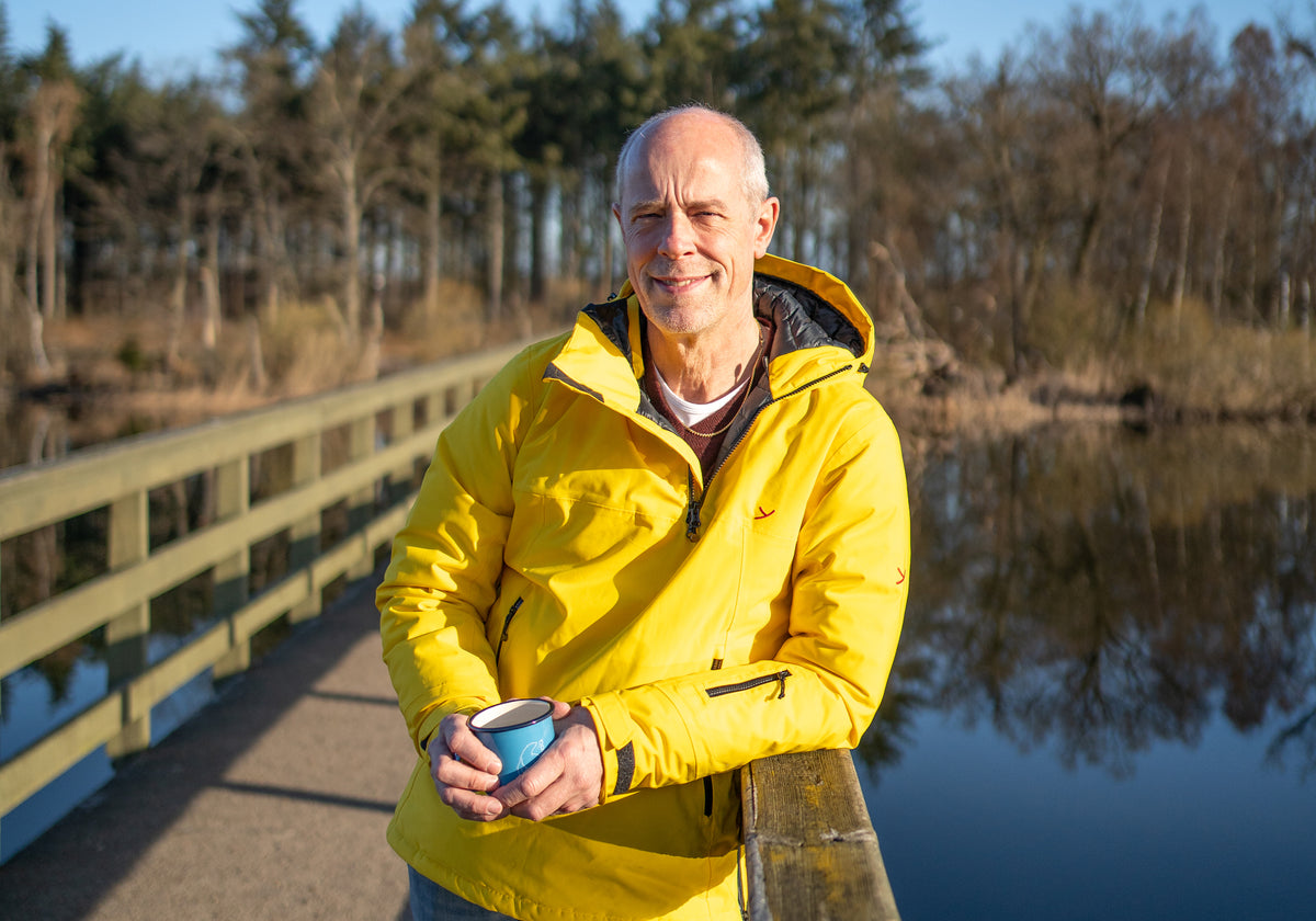 Erik J. Møller holding a blue Madam Blå enamel cup while outdoors.