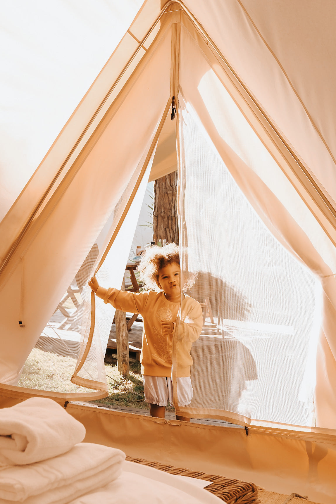 A young child looking through the mesh entrance of a luxury Nordisk cotton glamping tent.